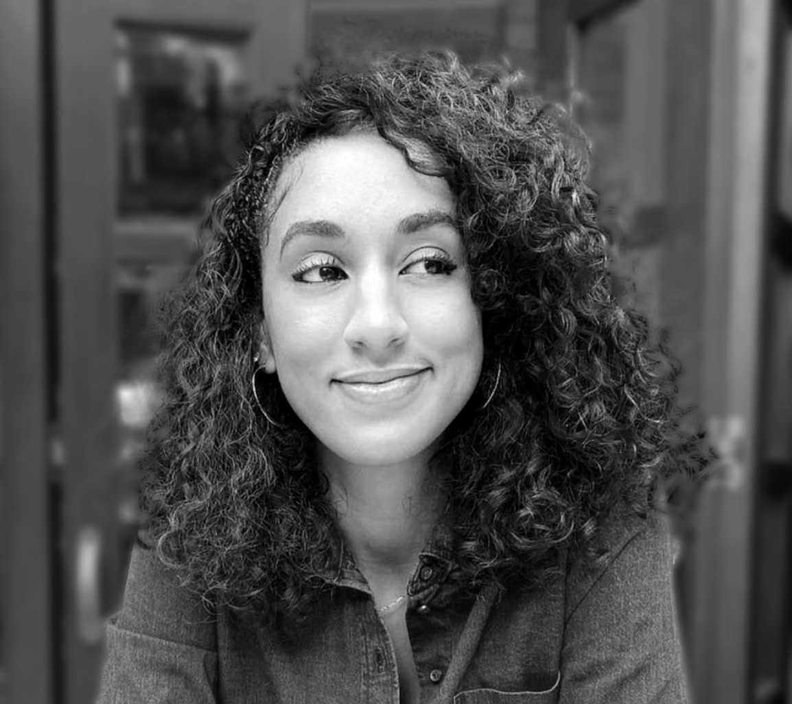 Black-and-white portrait of Ashleigh Ellis smiling and glancing to the side.