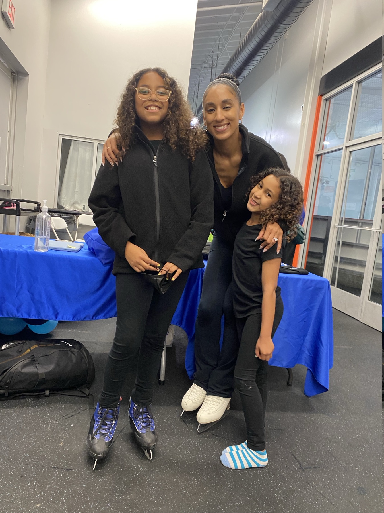 Ashleigh Ellis smiles with two young skaters at the rink.